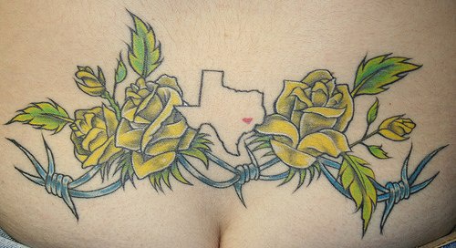 Lower back tattoo, nice, yellow roses on barbed fence, prison
