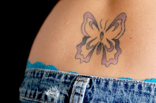 Tatuaje en el bajo de la espalda, mariposa en tinta morada