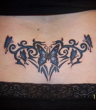 Le tatouage du bas du dos avec beaucoup de papillons bleu foncé volants dans l&quotentrelacs