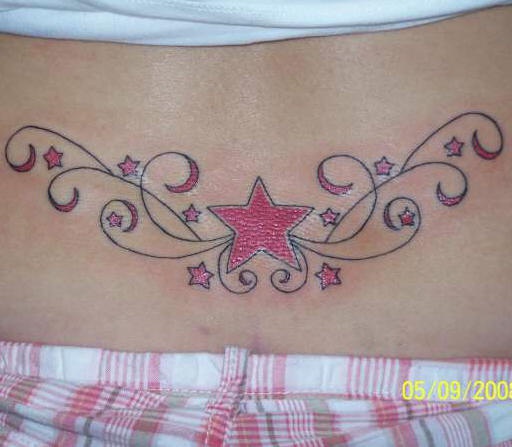 Lower back tattoo, big red star and many little stars in curls.