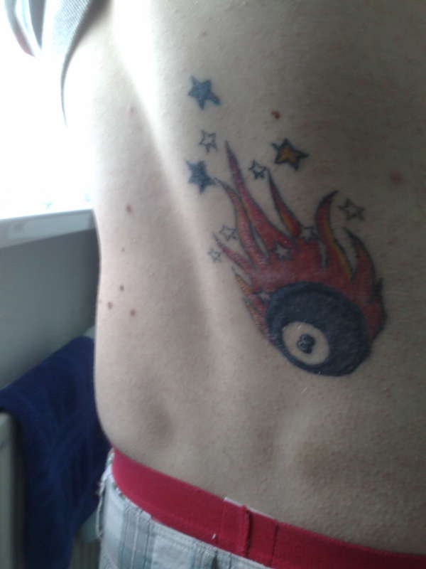 Le tatouage de bas du dos de balle de billard en flamme tombant comme une étoile