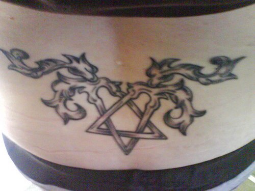 Lower back tattoo, two crossed pins decorated