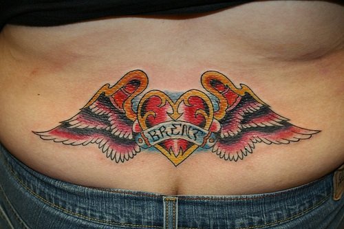 Tatuaje en el bajo de la espalda, corazón, decoración de alas en color