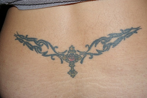 Lower back tattoo, cross styled with pattern on the sides