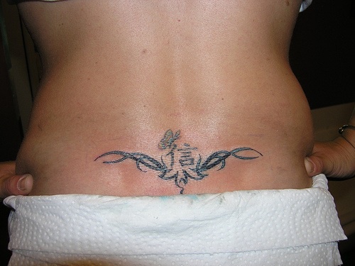 Tatuaje en el bajo de la espalda, estilo tribal, jeroglífico, mariposa