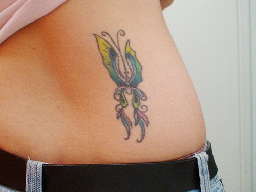 Stilisiertes Tattoo mit gestrecktem schmalem  Schmetterling am Becken