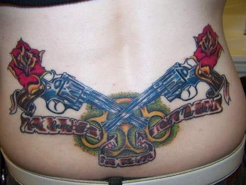Tattoo mit zwei blauen gekreuzten Pistolen  und Blumen am Becken