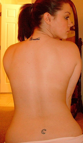 Lower back tattoo, little black star on the edge of moon