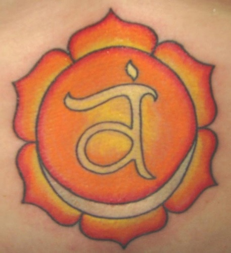Lower back tattoo, light orange flower, letter in centre