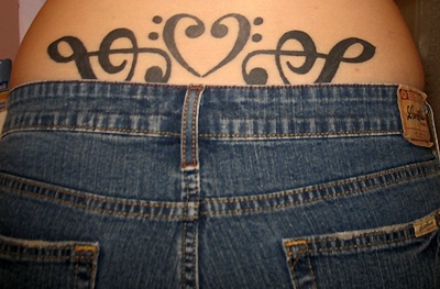 Lower back tattoo, black heart and two treble clefs