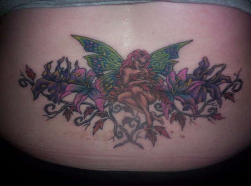 Lower back tattoo, red-haired fairy, green wings,in orchids