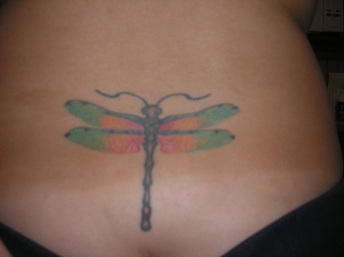 Tatuaje en el bajo de la espalda, libélula en color verde y rojo