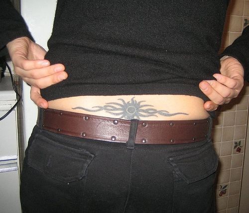 Le tatouage de bas du dos avec un soleil noir en style agitant
