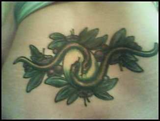 Lower back tattoo, two snakes hold an egg