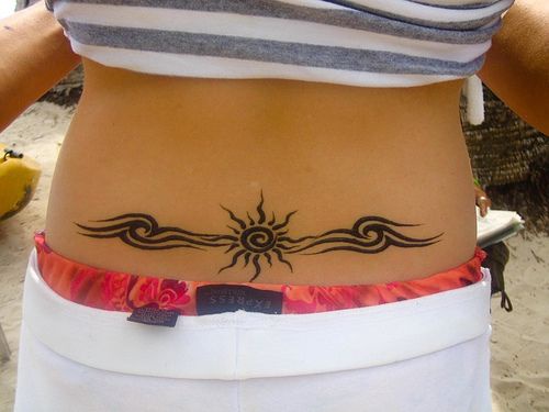 Lower back tattoo, black curled sun in waves