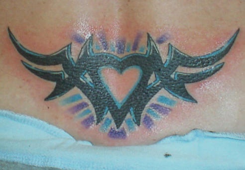 Tattoo mit schwarzem Herzen und buntem Schein am Becken