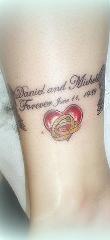 el tatuaje conmemorativo de un corazon rojo con dos anillos de oro, nombres y una fecha hecho en la pierna