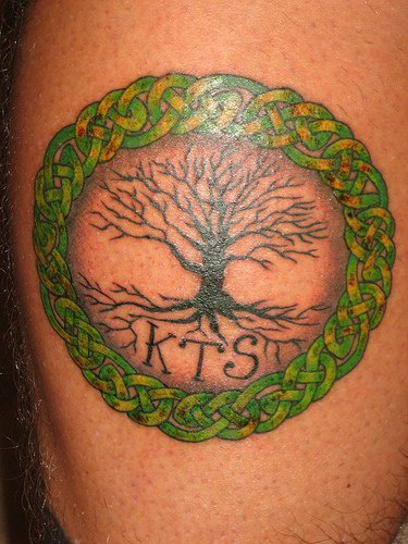 el tatuaje de un arbol de la vida con iniciales en un circulo de entrelazado de color verde
