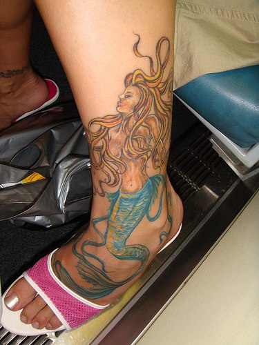Tatuaggio grande sulla gamba e sul piede la sirena con la coda azzurra
