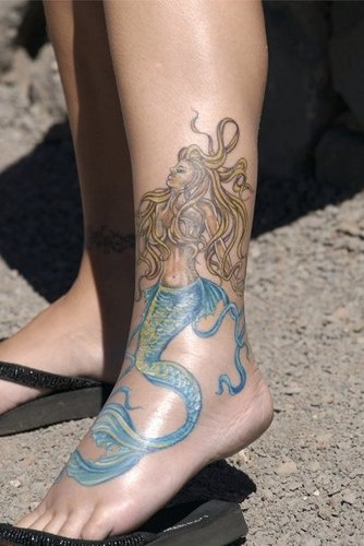 Tatuaggio bellissimo sulla gamba la sirena con la coda azzurra