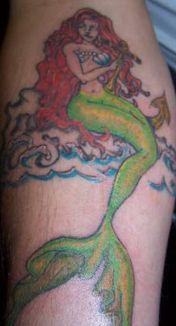 Sirène aux cheveux rouge avec le tatouage brassard de mer