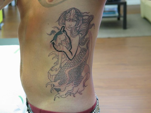 Tatuaggio stilizzato sul fianco la sirena nera con la maschera