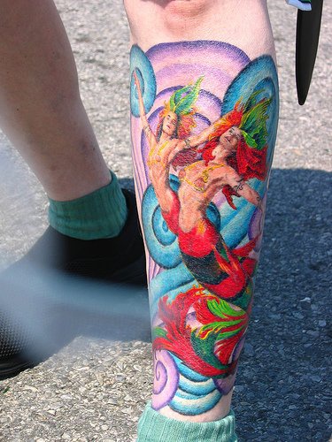 Tatuaggio colorato sulla gamba la sirena con il suo amico