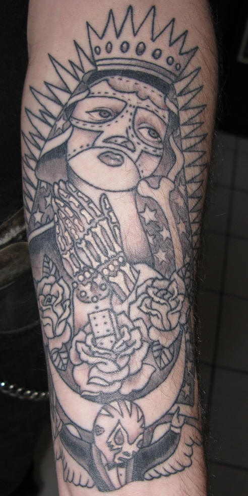 el tatuaje con muchos detalles incluyendo la virgen de guadalupe, manos orantes, el domino, y un luchador de la lucha libre hecho en el brazo