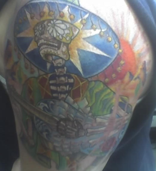 el tatuaje de un esqueleto mexicano hecho en varios colores en el brazo