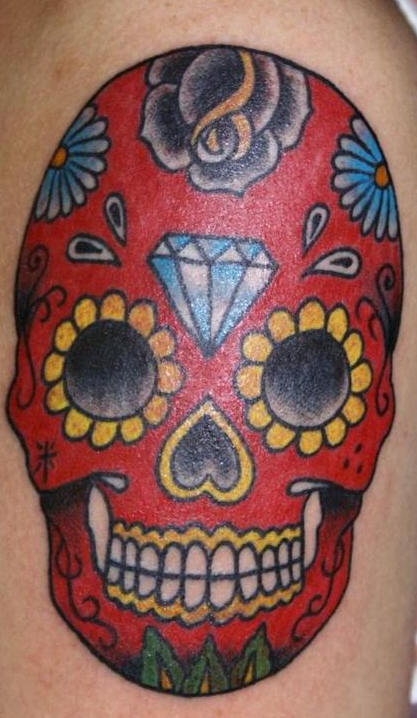 el tatuaje de una calavera mexicana roja con un diamante en su frente