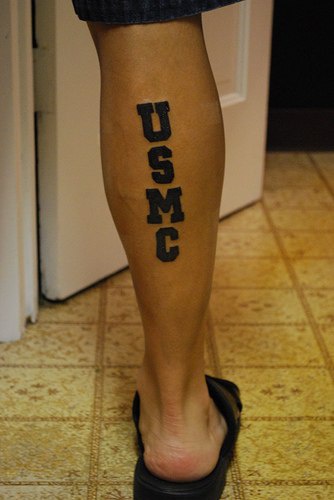 el tatuaje de letras &quotUSMC" de color negro en la pierna