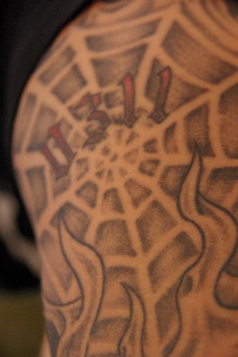 el tatuaje de una telaraña en llamas de fuego con el numero &quot0311" hecho con tinta negra