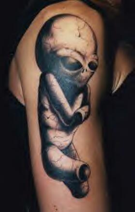 el tatuaje de un alienigena sin manos ni piernas hecho en el brazo