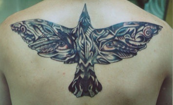 El tatuaje muy detallado de un pájaro con ojos en sus alas hecho en la espalda