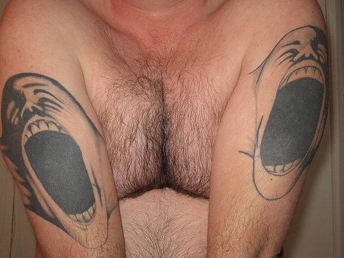 el tatuaje doble hecho en los dos brazos de dos caras gritando