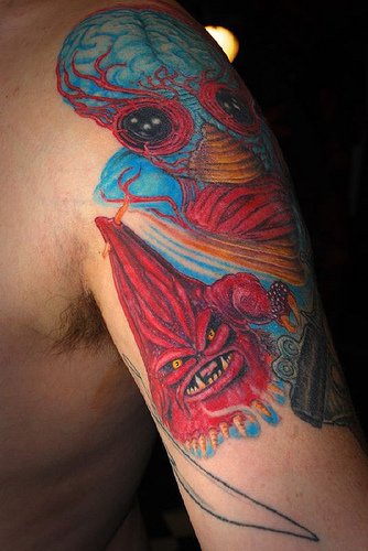 el tatuaje detallado y muy colorado de dos monstruos hecho en el hombro