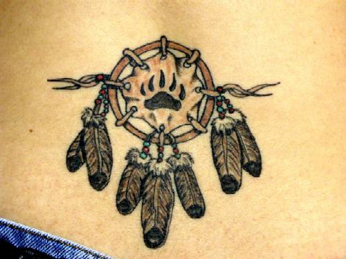 el tatuaje pequeño de un talisman atrapasueños indio con plumas y una huella de oso en el centro