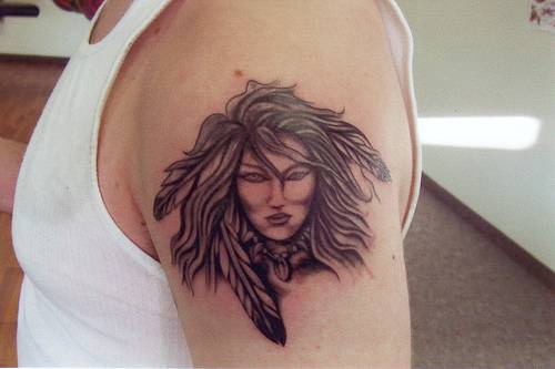 el tatuaje de una mujer india con plumas en el cabello hecho en el hombro
