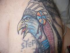 el tatuaje de una aguila con corona de pluumas hecho en color
