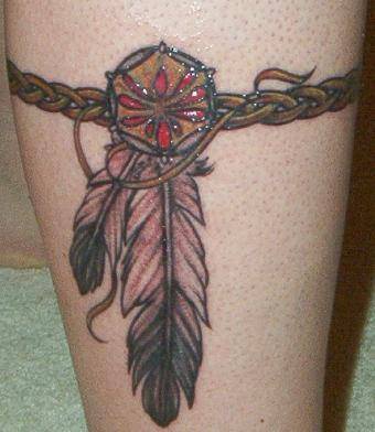 el tatuaje en forma de brazalete trenza con un talisman y plumas indias