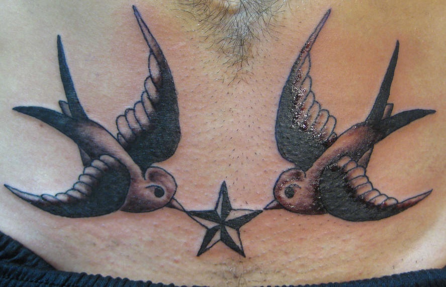 el tatuaje simetrico de dos gorriones con una estrella nautica