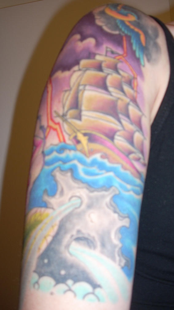 el tatuaje colorado de un barco en el mar durante una tormenta hecho en el brazo