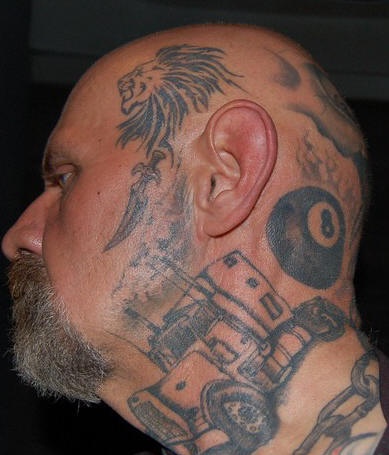 Leone e la macchina tatuati sulla faccia e collo