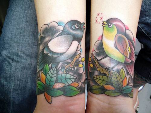 Colorful traditional tattoo with birds on hands