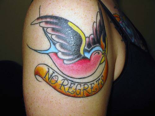 Tatuaje tradicional  en el hombro el pájaro en color con la inscripción &quotno regrets" en el pico