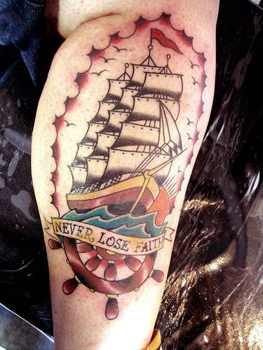 Tatuaje tradicional en color con la nave e inscripción &quotnever lose faith"