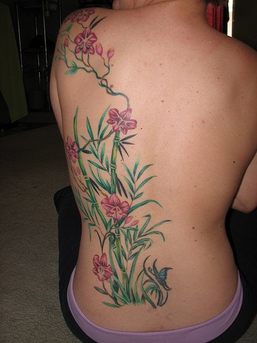 el tatuaje grande de las orquideas creciendo entre el babmu hecho en la espalda