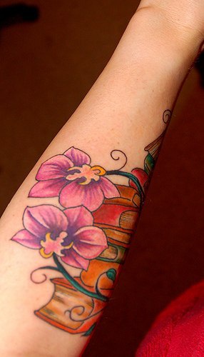 el tatuaje leniado coloradocon orquideas de color morado hecho en la mano