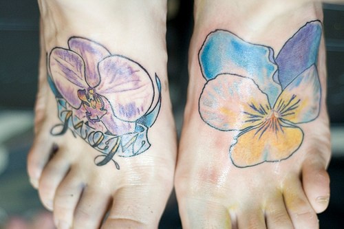 el tatuaje de dos orquideas coloradas hecho cada uno en un pie