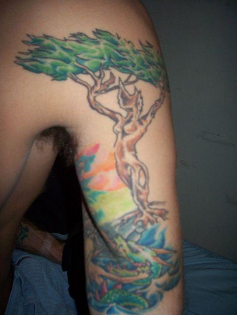 Tatuaje en el brazo, tronco de árbol con figura de mujer
